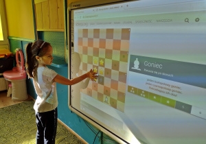 dziewczyna wykonuje zadania szachowe na tablicy interaktywnej